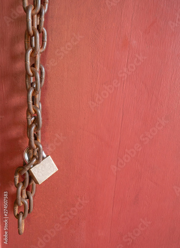 the padlock with old chain on the red wooden door