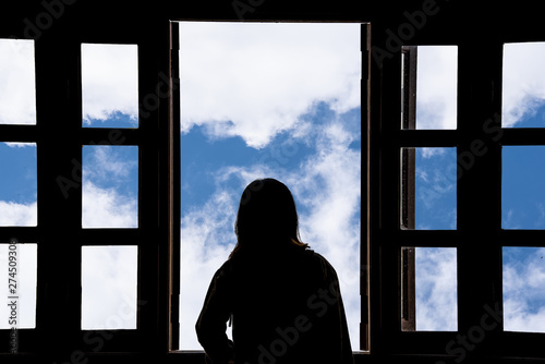 Silhouette woman looking out of window see blue sky and clouds.Freedom concept.