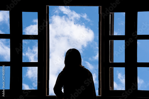 Silhouette woman looking out of window see blue sky and clouds.Freedom concept.