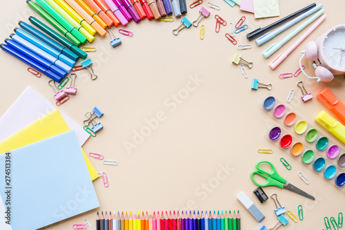 School supplies stationery, colour pencils, paints, paper on pastel orange background, back to school concept with free copy space for text, modern elementary education. Kids desk, flat lay, overhead