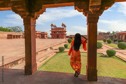 Fatehpur Sikri red sandstone architecture with view of woman tourist posing at the ancient fort city at Agra India  photo