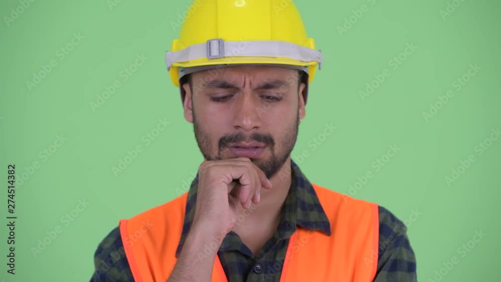 Face of stressed young bearded Persian man construction worker thinking