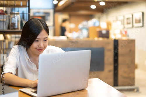 Young Asian woman working with a laptop in the coffee shop cafe office.