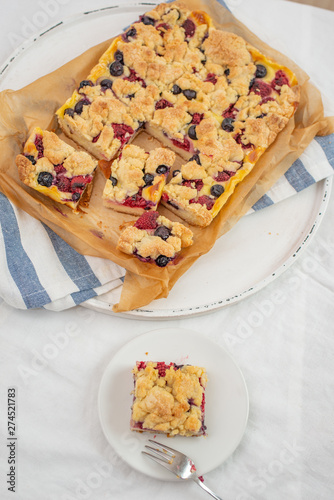 crumble cake in a baking form and pieces of the cake on a table