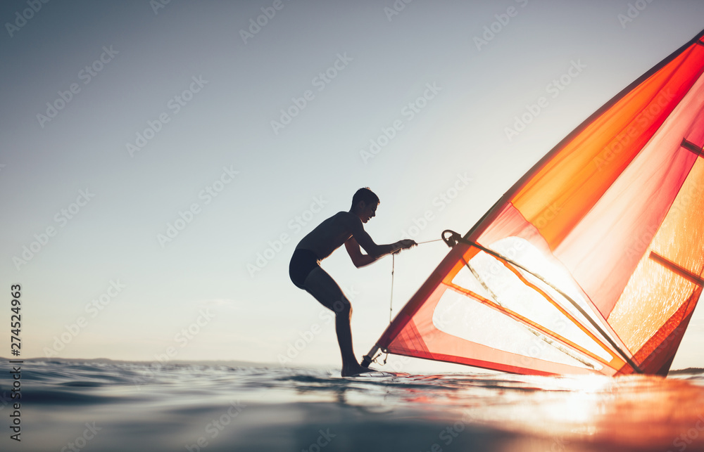 Silhouette of windsurfer uplift windsurf board sail. Windsurfing, sailing, surfing, water sports