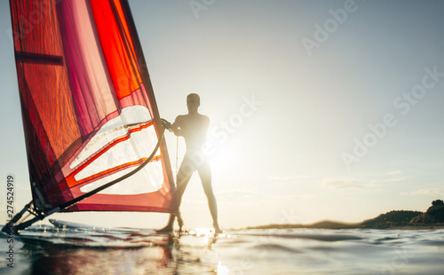 Windsurfer on windsurf board on the sunset sea, copy space