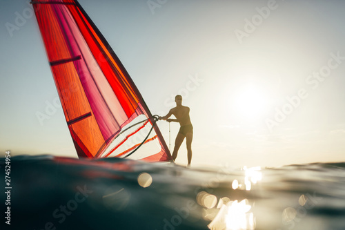 Young man balancing on windsurf board. Windsurfing, sailing, surfing, water sports