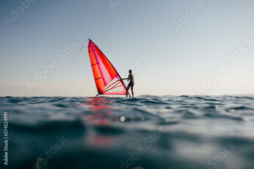 Surfer uplift windsurf board. Low angle view of windsurfer on the board