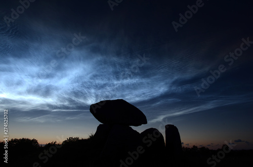 Slika na platnu Steel blue noctiliucent clouds with the silhouette of a round barrow as foreground