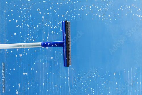 Rubber squeegee cleans window. Clears a stripe of soaped window. Cleaning service concept.