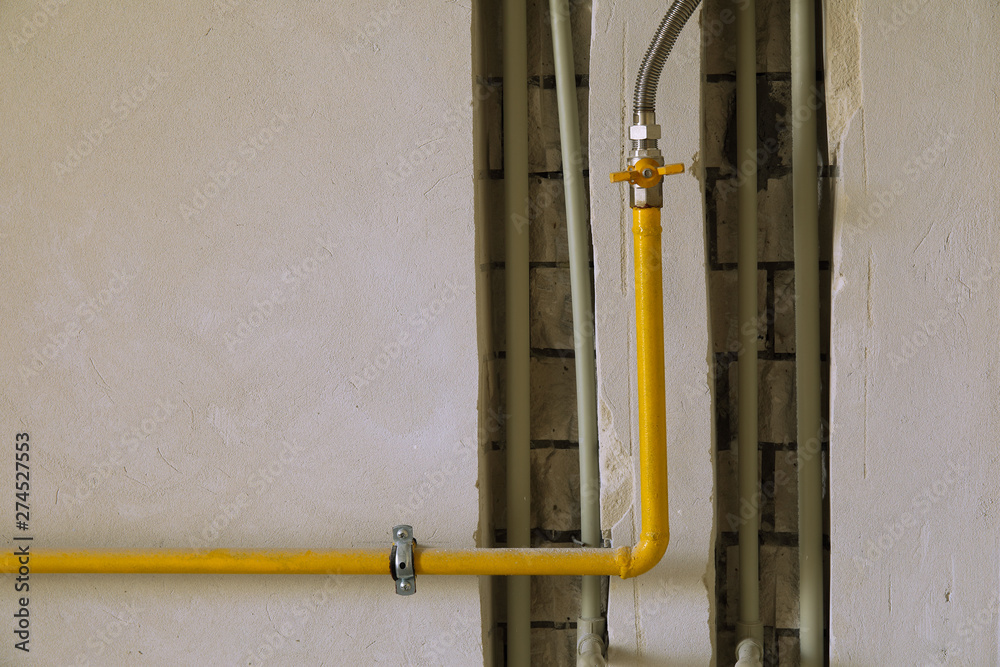 Yellow gas pipe on residential house wall.