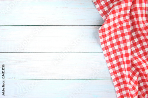 Red checked picnic towel cloth on blue wooden empty space background.
