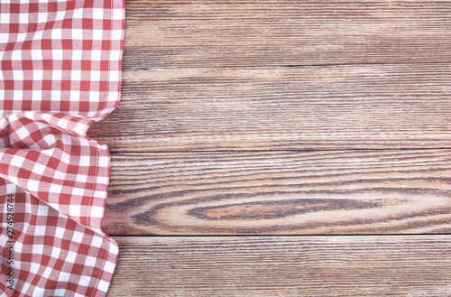 Red checked picnic towel cloth on wooden empty space background.