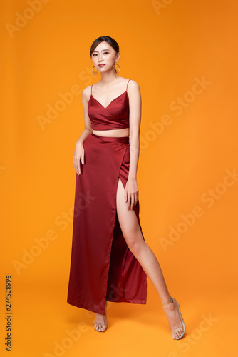 Fototapeta Full length portrait of young sexy woman in red dress  standing and posing again