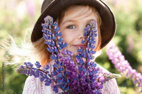 Portrait of a pretty girl in a brown hat with bouquets of lupins in the face photo