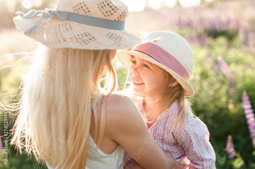 smiling pretty girl at her mother in her arms in the field at sunset