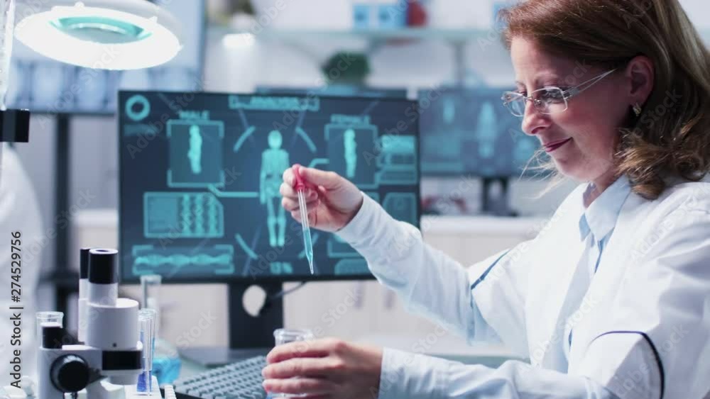 Female scientist works with test samples from tubes. In the background a computer displays an advanced body scan Female scientist works with test samples from tubes. In the background a computer displays an advanced body scan