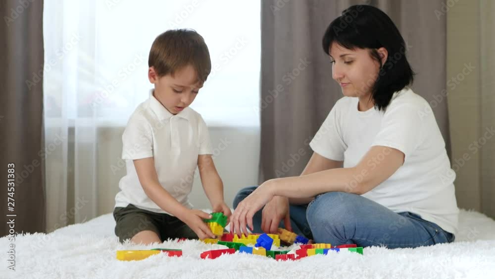 Happy mother spends time with her child playing in colored blocks. Happy mother spends time with her child playing in colored blocks.