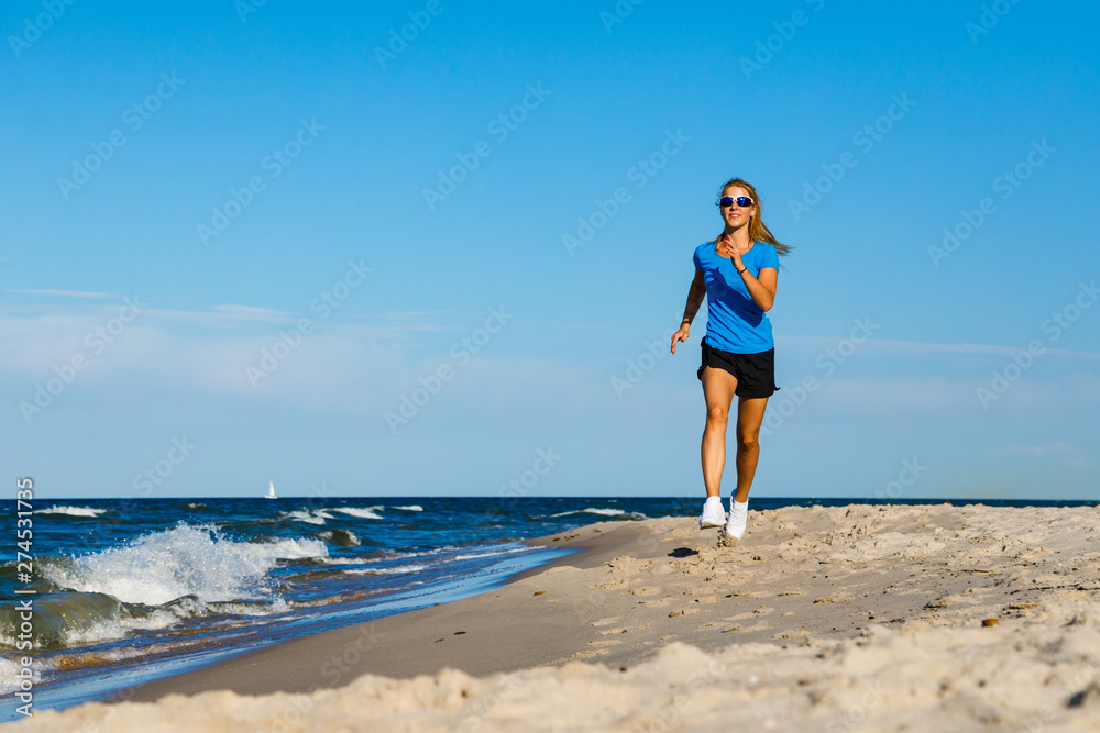 Young woman running, jumping on beach