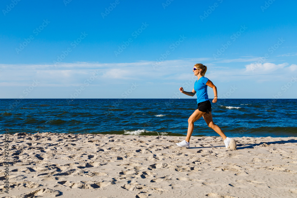 Young woman running, jumping on beach - obrazy, fototapety, plakaty 