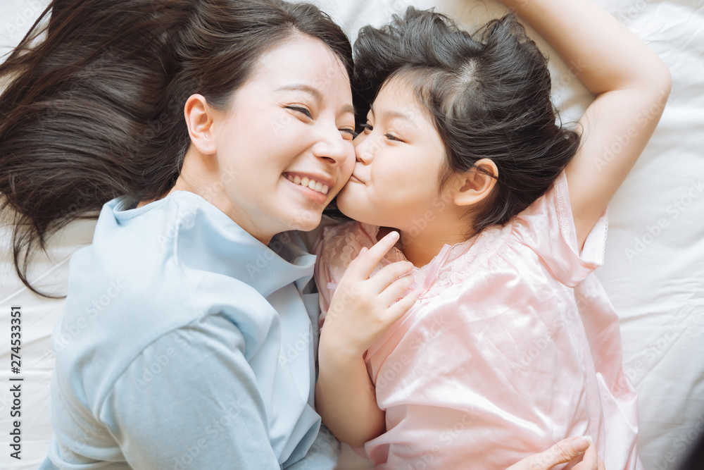 Daughter kisses her mother's cheek. and hugging in the bedroom .Happy Asian family Daughter kisses her mother's cheek. and hugging in the bedroom .Happy Asian family