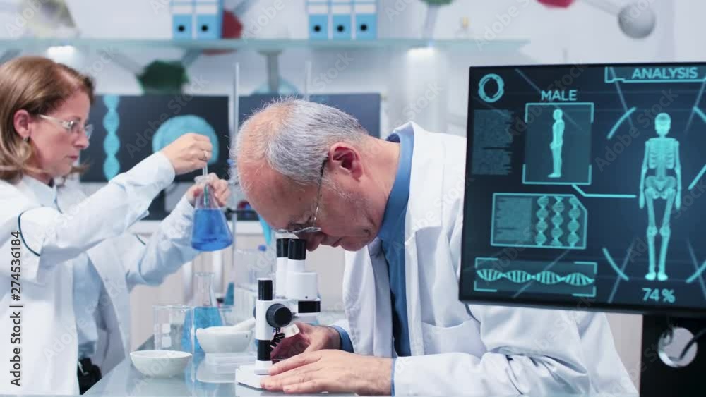 Medium shot of mature scientists working in busy modern laboratory