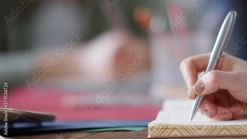 Wallpaper Mural Panning close-up hand shot of young woman with neat manicured beige nails tentatively writing with silvery ballpoint pen in notebook Torontodigital.ca