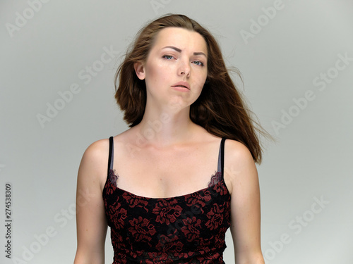 Closeup portrait of pretty girl, brunette woman 30 years old on a light gray background with beautiful dark hair and excellent skin of the face and body. She shows emotions, smiles, wonders.