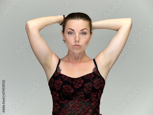 Closeup portrait of pretty girl, brunette woman 30 years old on a light gray background with beautiful dark hair and excellent skin of the face and body. She shows emotions, smiles, wonders.