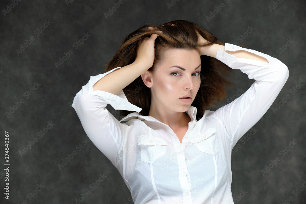Closeup portrait of pretty girl, brunette woman 30 years old on a light gray background in a white shirt with dark hair and excellent skin. She shows emotions, smiles, wonders. Closeup portrait of pretty girl, brunette woman 30 years old on a light gray background in a white shirt with dark hair and excellent skin. She shows emotions, smiles, wonders.