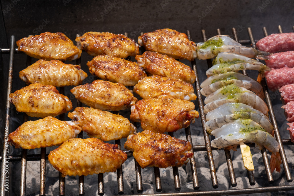 Mixed assortment of marinated meat, chicken, and prawns grilling on hot coals on a BBQ Mixed assortment of marinated meat, chicken, and prawns grilling on hot coals on a BBQ