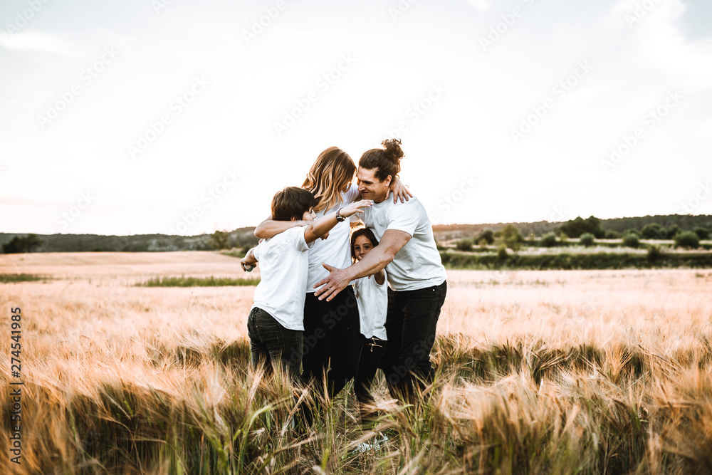 Happy family hugging in the field and smiling. Family in a sunset Happy family hugging in the field and smiling. Family in a sunset