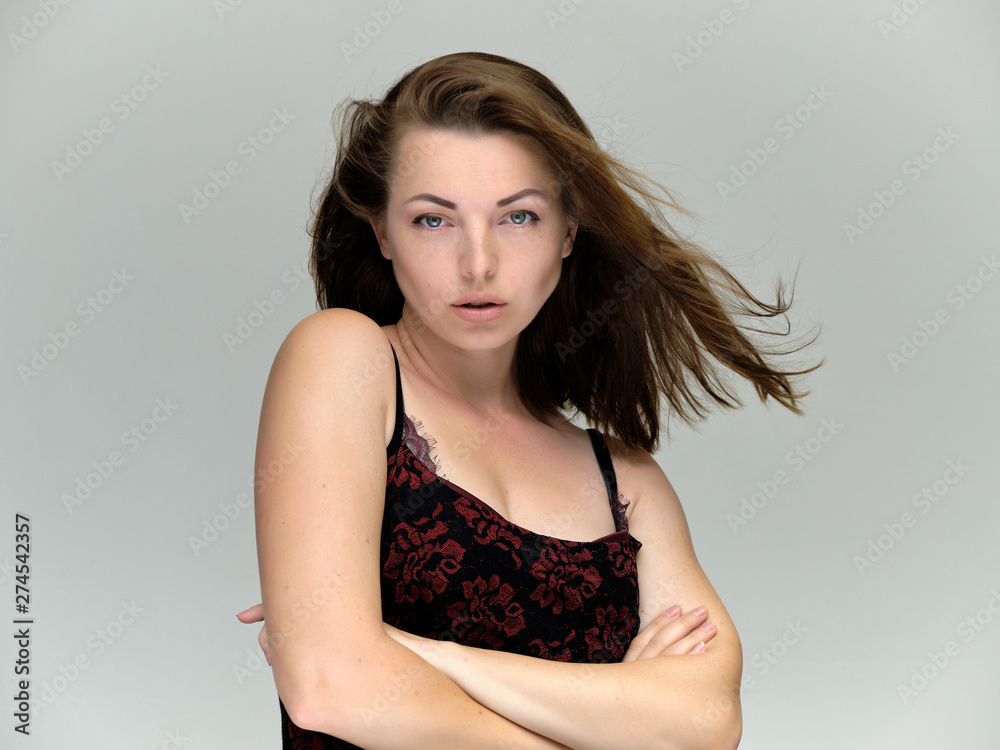 Fototapeta premium Closeup portrait of pretty girl, brunette woman 30 years old on a light gray background with beautiful dark hair and excellent skin of the face and body. She shows emotions, smiles, wonders.