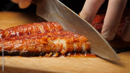 Chef cutting fried eel on the board.