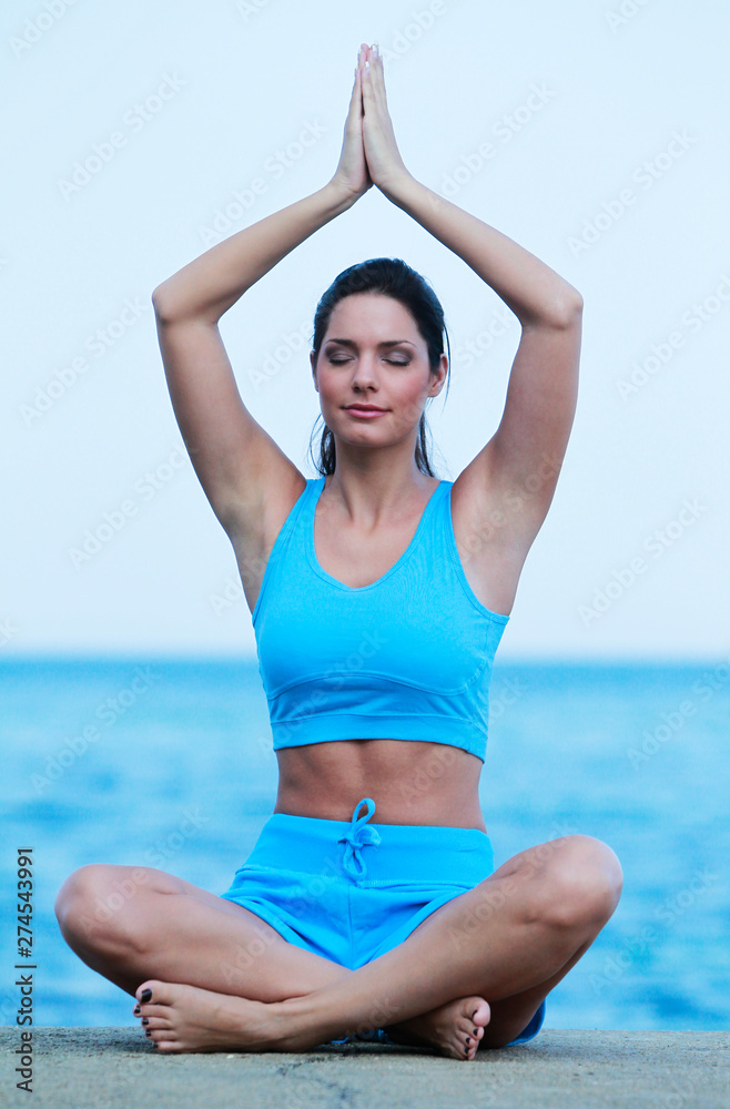Jeune femme faisant son Yoga face à la mer Jeune femme faisant son Yoga face à la mer