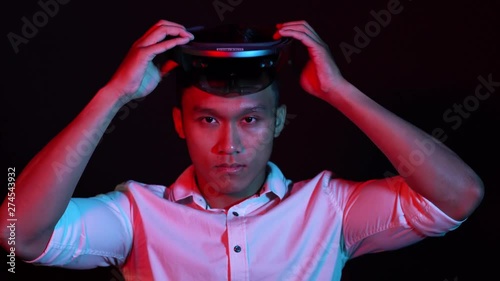 Business man try vr glasses hololens in the dark room. Colorful portrait of young Asian boy wearing virtual reality headset.