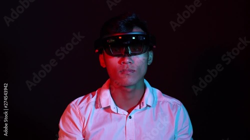 Business man try vr glasses hololens in the dark room. Colorful portrait of young Asian boy wearing virtual reality headset.