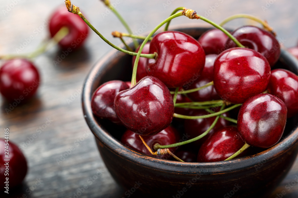 Fresh sweet cherries bowl with leaves on a wooden table Fresh sweet cherries bowl with leaves on a wooden table