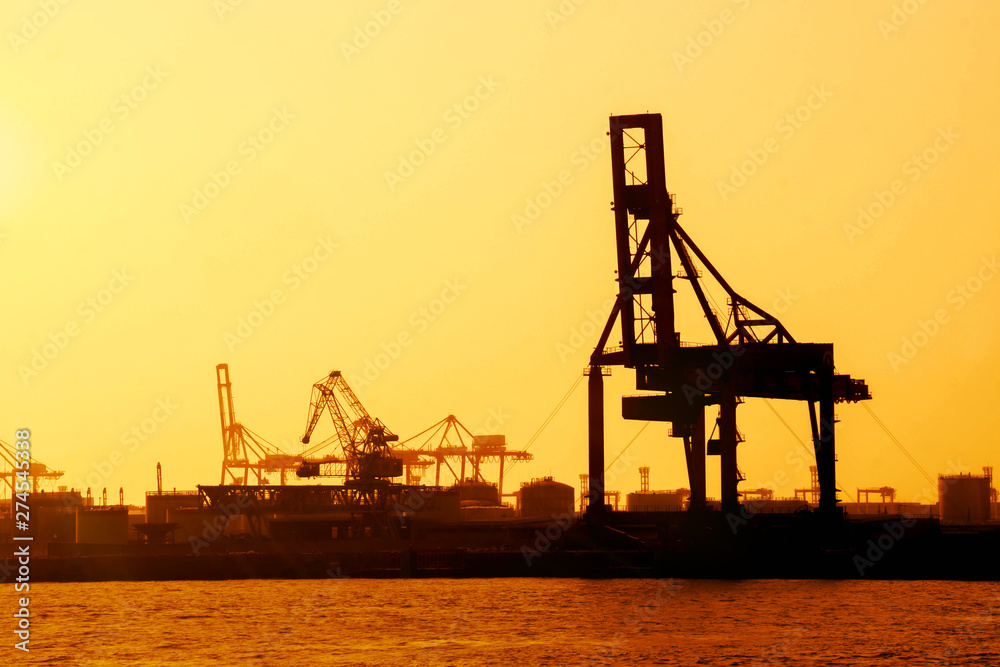 Silhouette of container crane are loading at Osaka port evening and gantry crane working background.