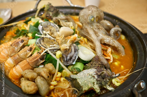 A hot Korean seafood stew with various ingredients including small octopus, shrimps, avalons, trumpet shells, warty sea squirts, and vegetables. photo