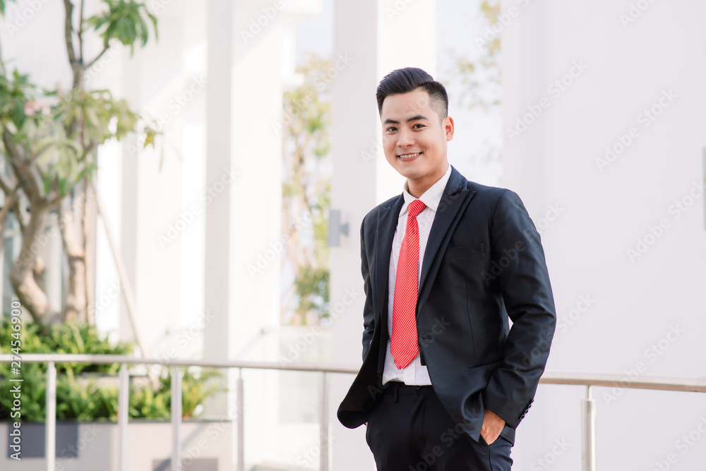Cheerful asian business man standing in park Cheerful asian business man standing in park
