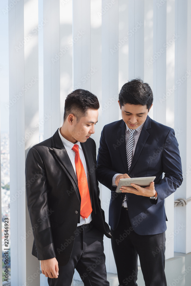 Two Vietnamese male coworkers talking and smiling Two Vietnamese male coworkers talking and smiling