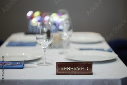 Restaurant reserved table sign with places setting and wine glasses ready for a party