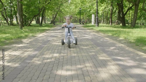 Wallpaper Mural Little girl rides a  bike in the Park. Happy child smiling and laughing. A little girl rides a bicycle a city public Park.  Torontodigital.ca