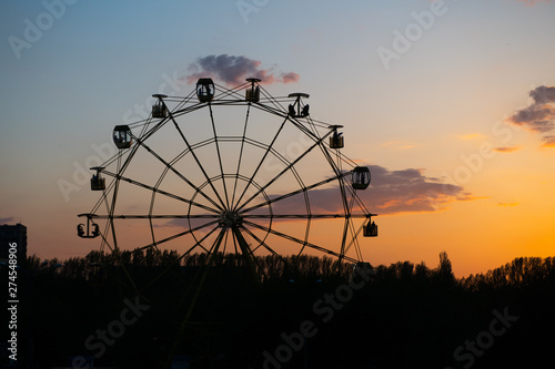 Silhouette of old soviet Ferris wheel against sunset sky