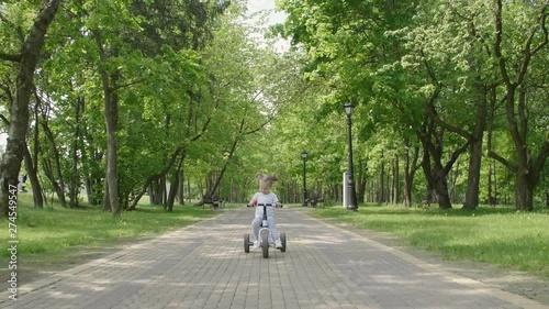 Wallpaper Mural Little girl rides a  bike in the Park. Happy child smiling and laughing. A little girl rides a bicycle a city public Park.  Torontodigital.ca