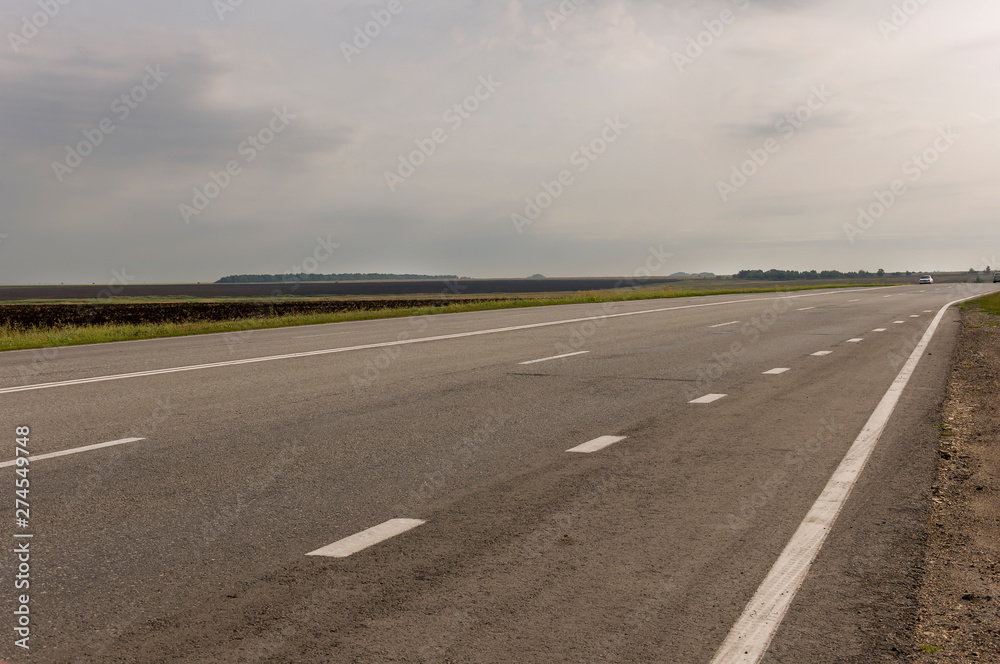 Big autumn field with trees far away and clouds in the blue sky. Asphalt road. Travelling Big autumn field with trees far away and clouds in the blue sky. Asphalt road. Travelling