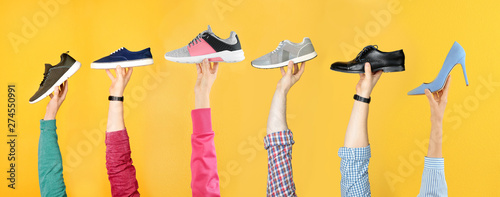 Tableau sur toile Set of people holding different stylish shoes on color background, closeup