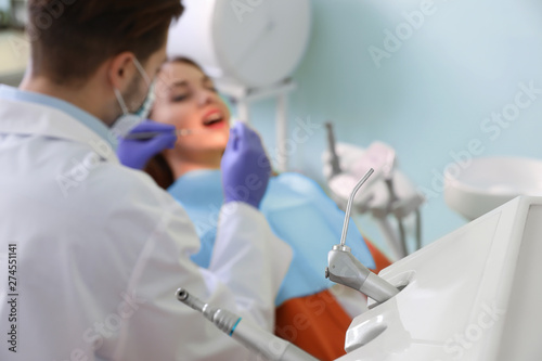 Closeup view of professional dentist's equipment and blurred doctor with patient on background. Space for text