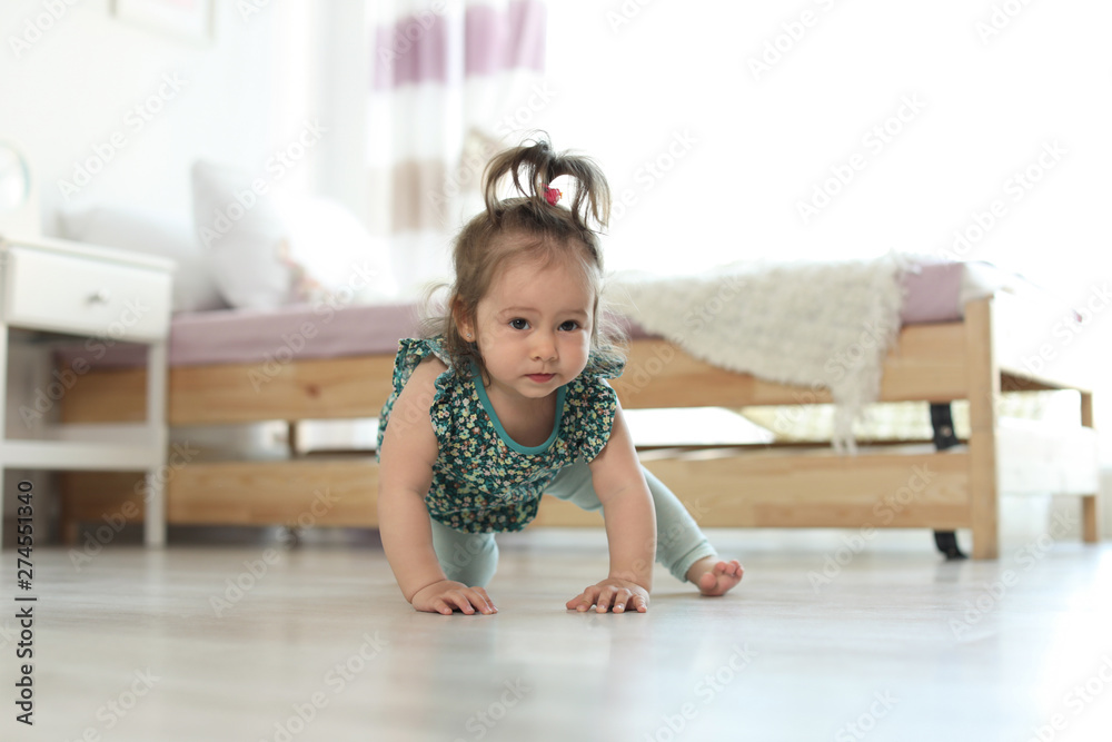 Naklejka premium Adorable little baby girl crawling on floor in room